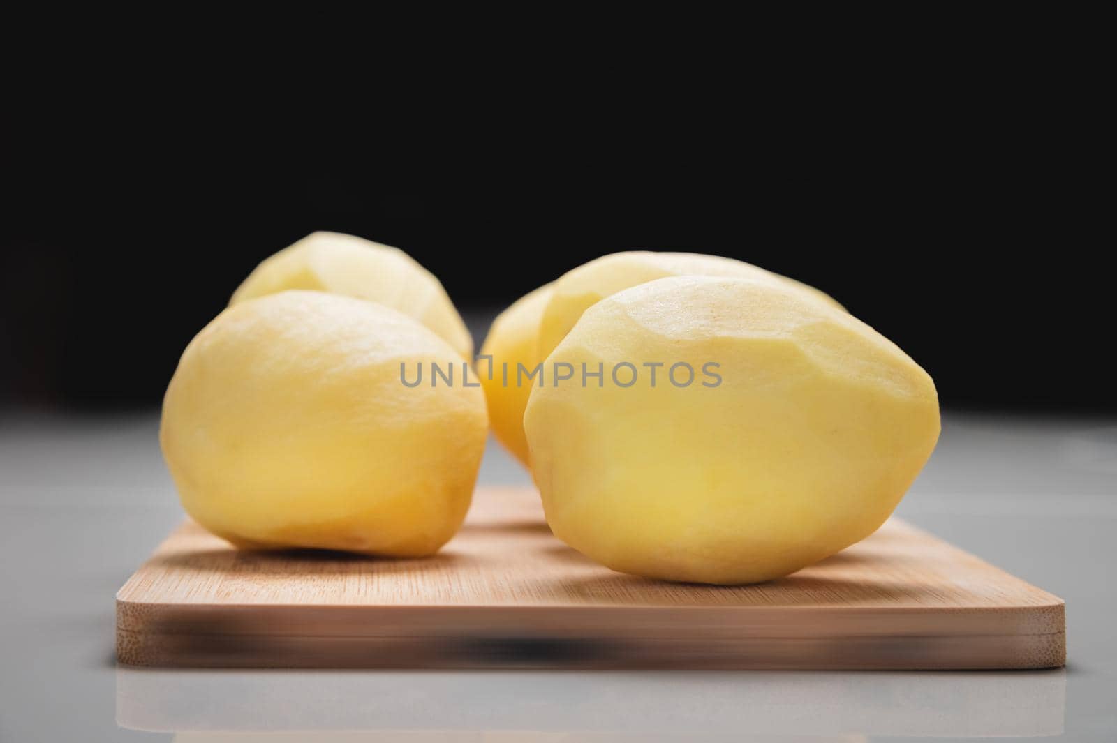 Close-up Several peeled potatoes on a wooden cutting board on a white table