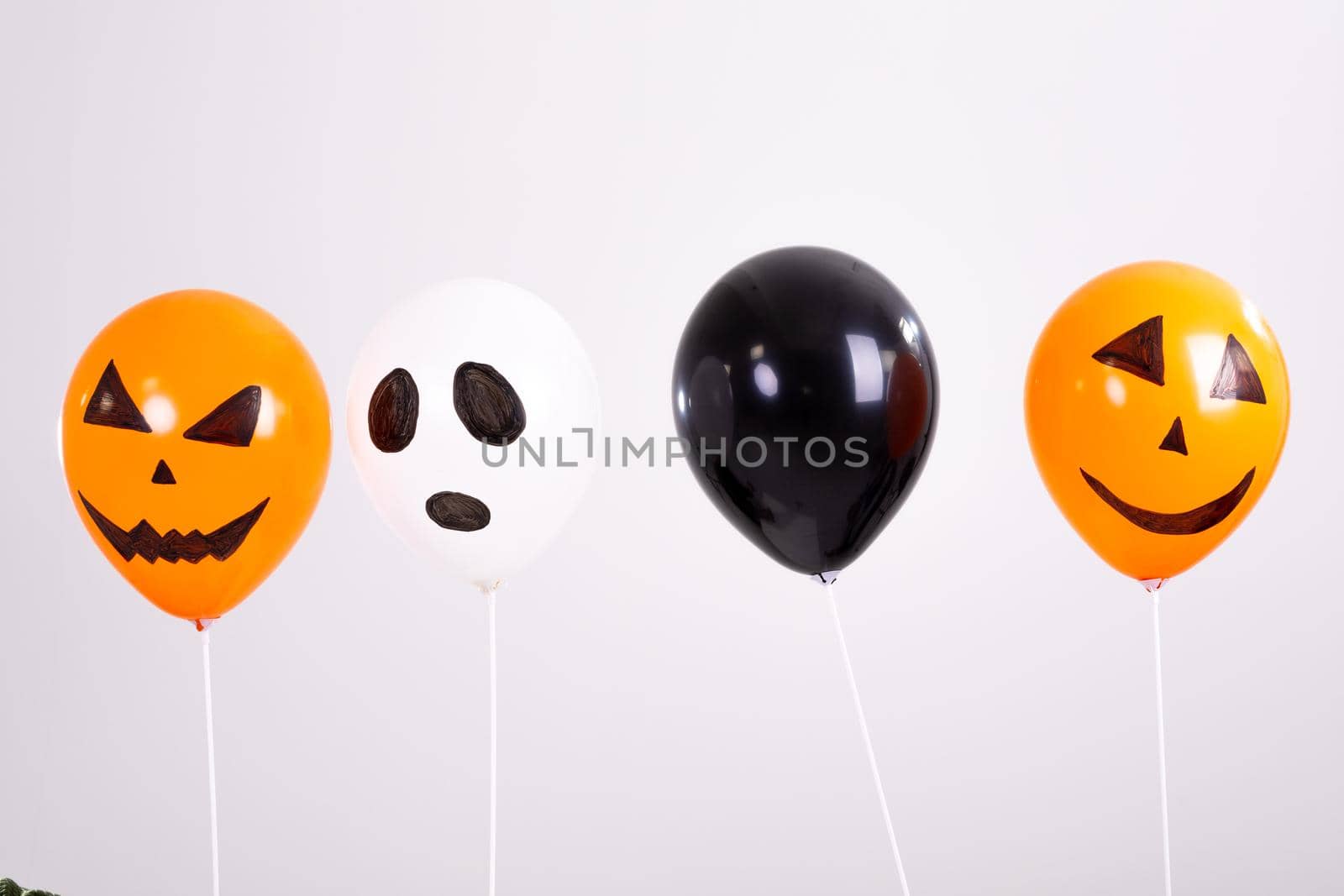 Orange, black and white halloween balloons over white background. halloween tradition and celebration concept digitally generated image.