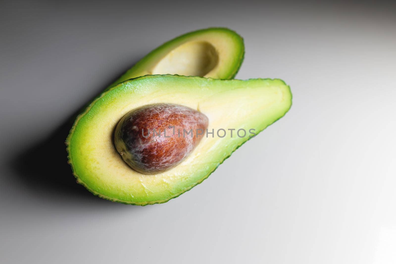 Avocado on old wooden table.Halfs on wooden bowl. Fruits healthy food concept