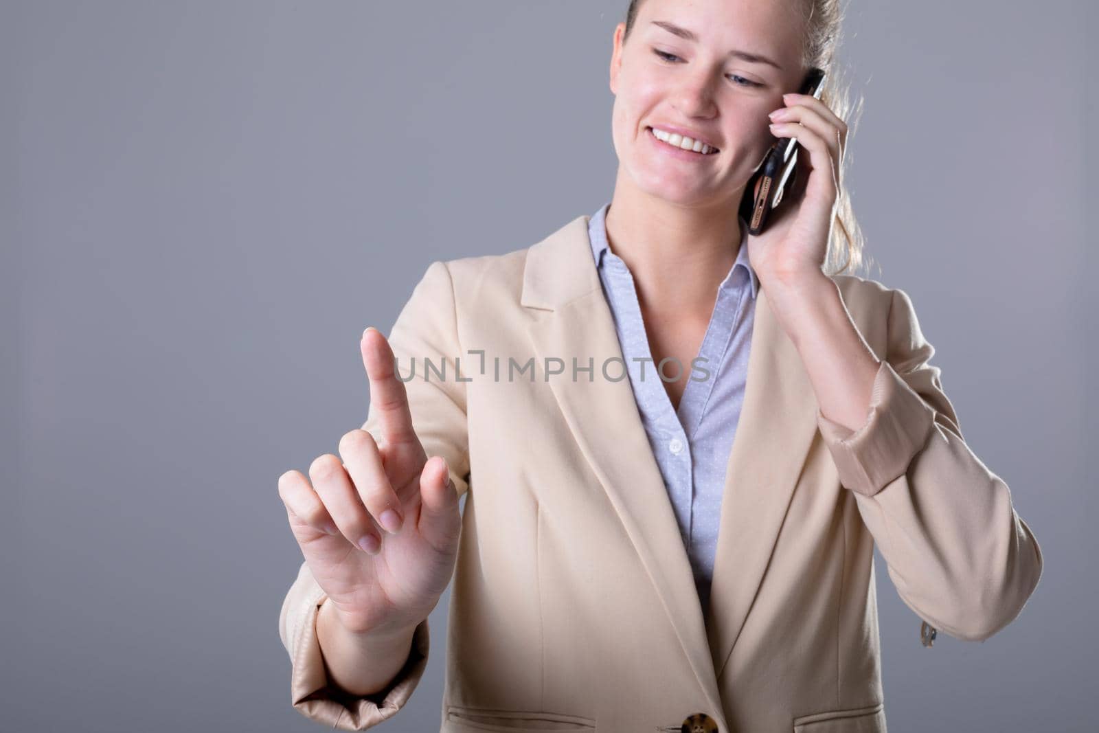Caucasian businesswoman talking on smartphone using virtual interface, isolated on grey background. business, technology, communication and growth concept.