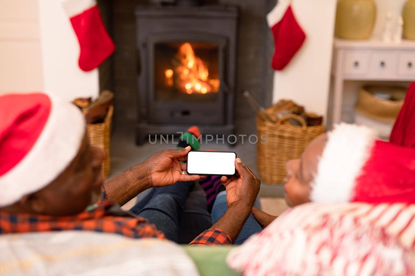 Back view of african american senior couple using smartphone with copy space at christmas time. retirement lifestyle and christmas festivities, celebrating at home.