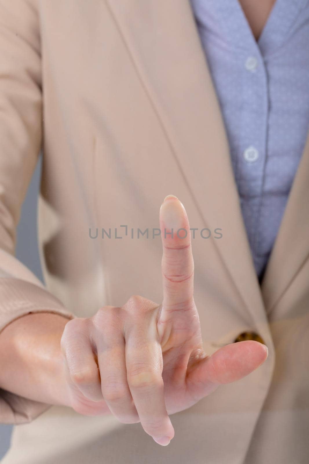 Midsection of caucasian businesswoman touching virtual interface on grey background by Wavebreakmedia