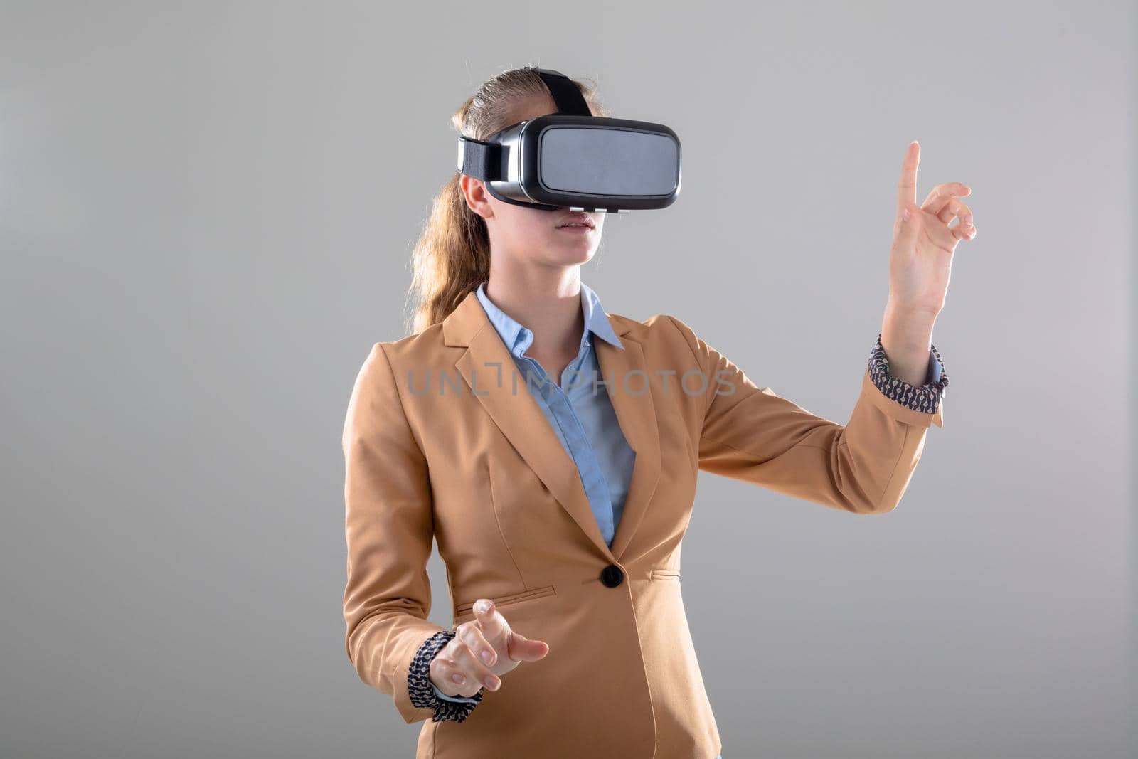 Caucasian businesswoman wearing vr headset touching virtual interface, isolated on grey background. business, technology, communication and growth concept.