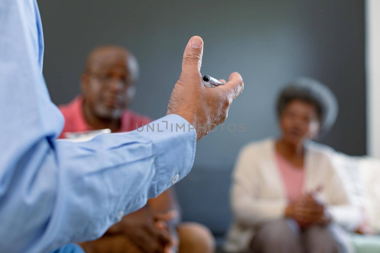 Hand of mixed race senior male counsellor advising diverse group of senior friends by Wavebreakmedia