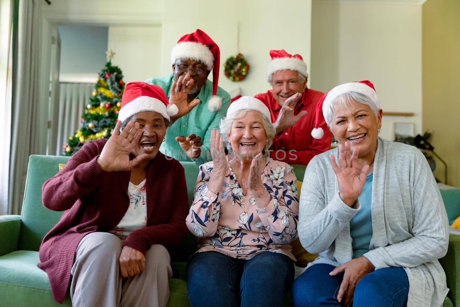 Group of happy diverse group of senior friends in santa hats having video call at christmas time. christmas, festivity and communication technology.