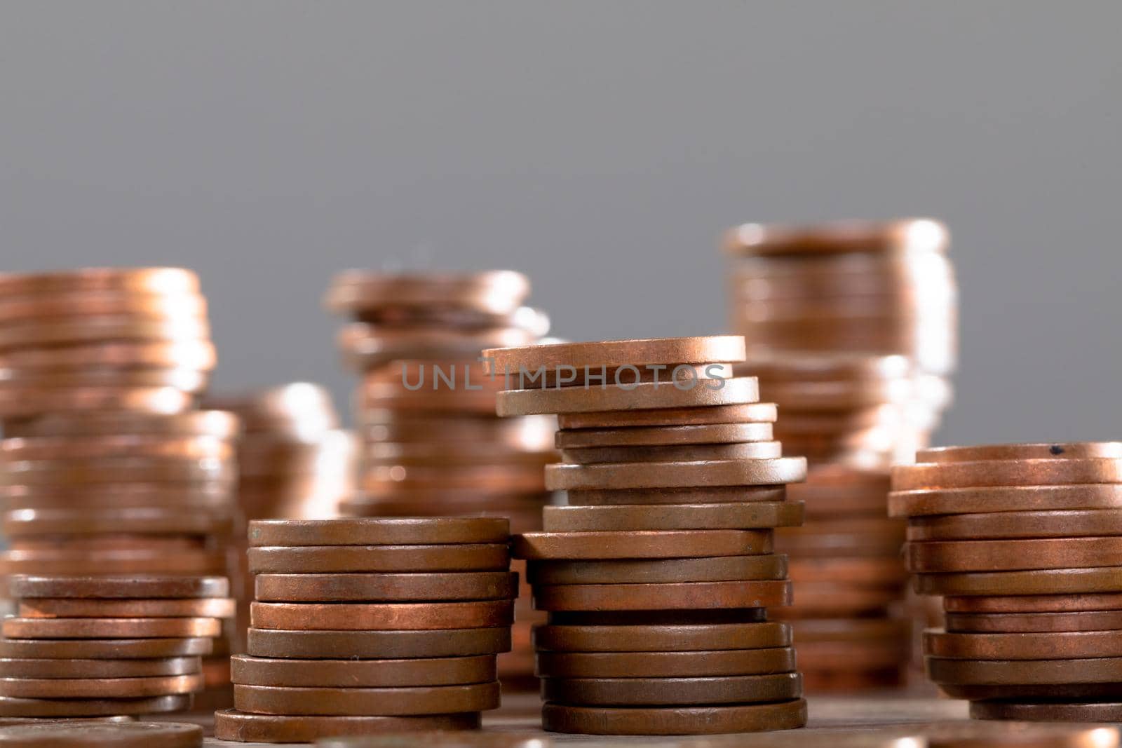 Close up of piles of coins on table, isolated on grey background by Wavebreakmedia