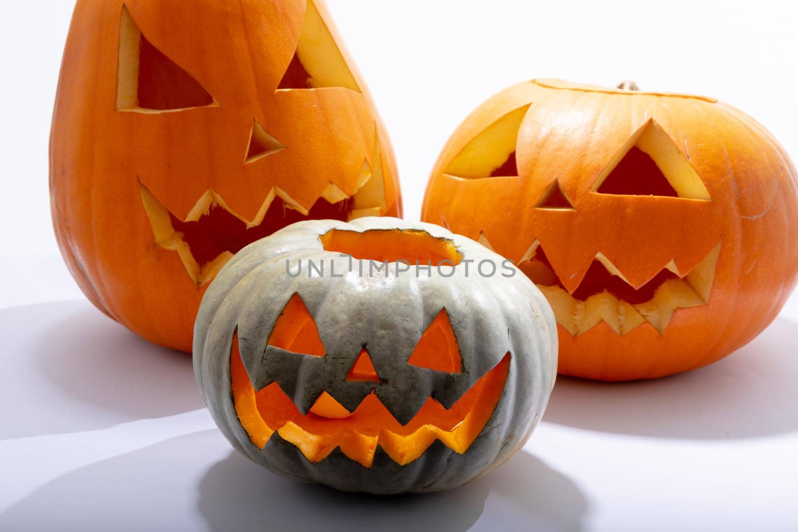 Composition of three halloween carved pumpkins with copy space on white background. halloween tradition and celebration concept.
