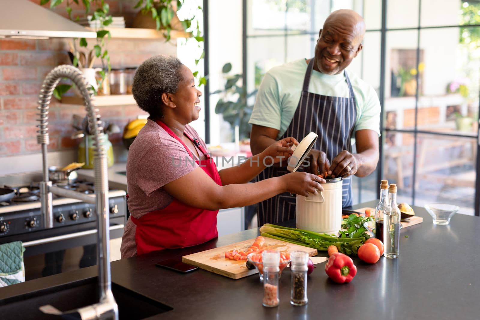 Happy african american senior couple cooking together in kitchen. retirement lifestyle, leisure and spending time at home.