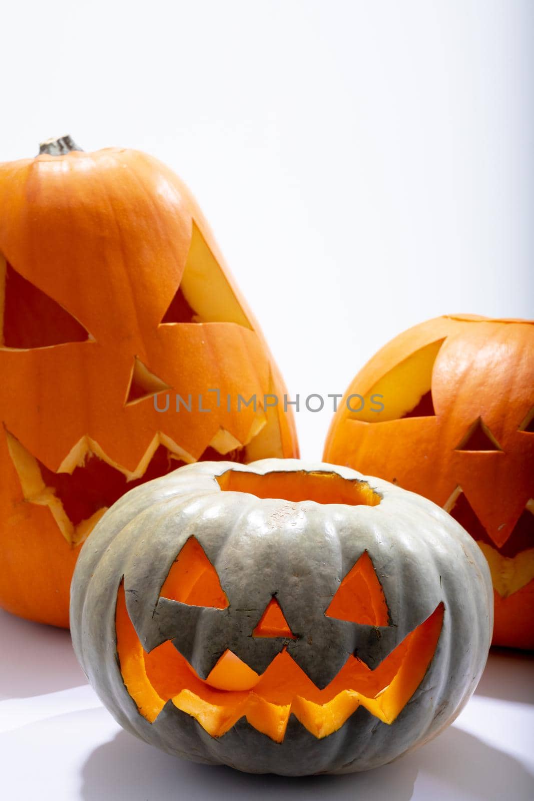 Composition of three halloween carved pumpkins with copy space on white background by Wavebreakmedia
