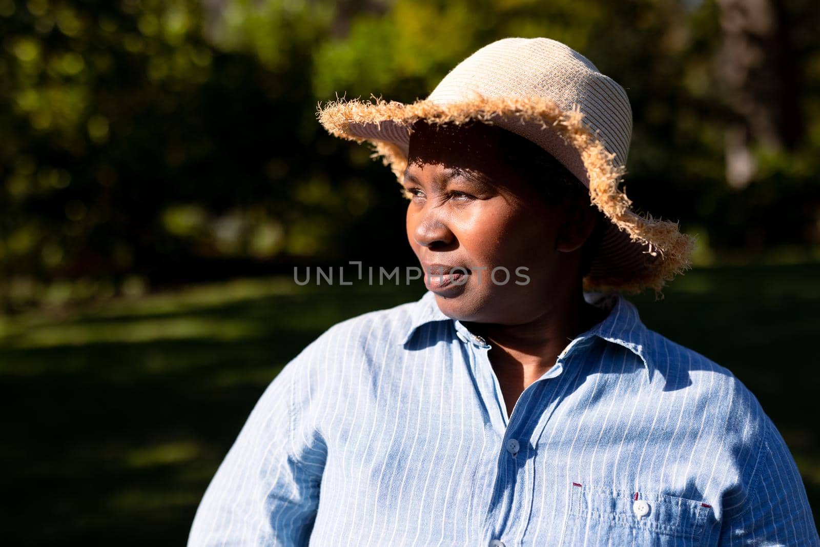 Portrait of african american senior woman wearing hat, looking into distance outdoors. retirement lifestyle, spending time at home and garden.