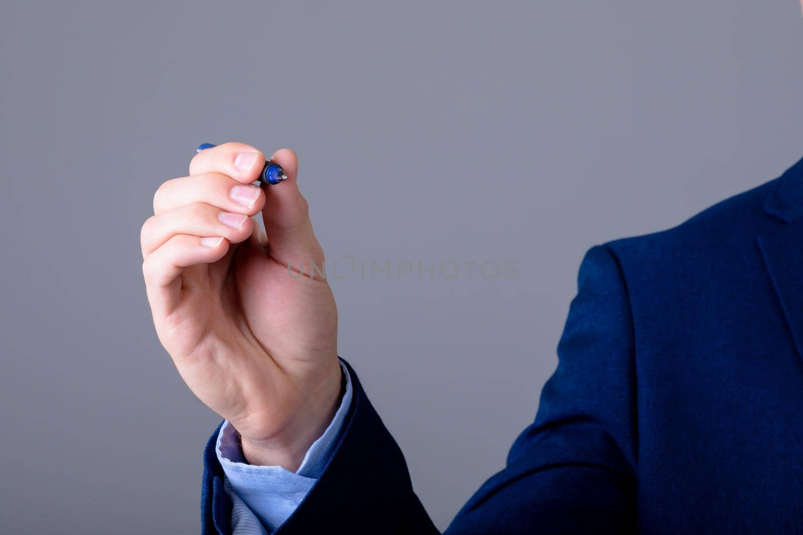 Midsection of caucasian businessman holding pen, isolated on grey background. business technology, communication and growth concept.