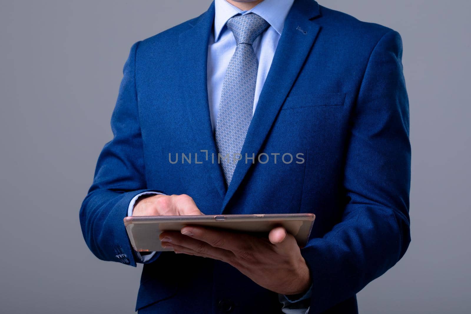 Midsection of caucasian businessman using digital tablet, isolated on grey background. business technology, communication and growth concept.