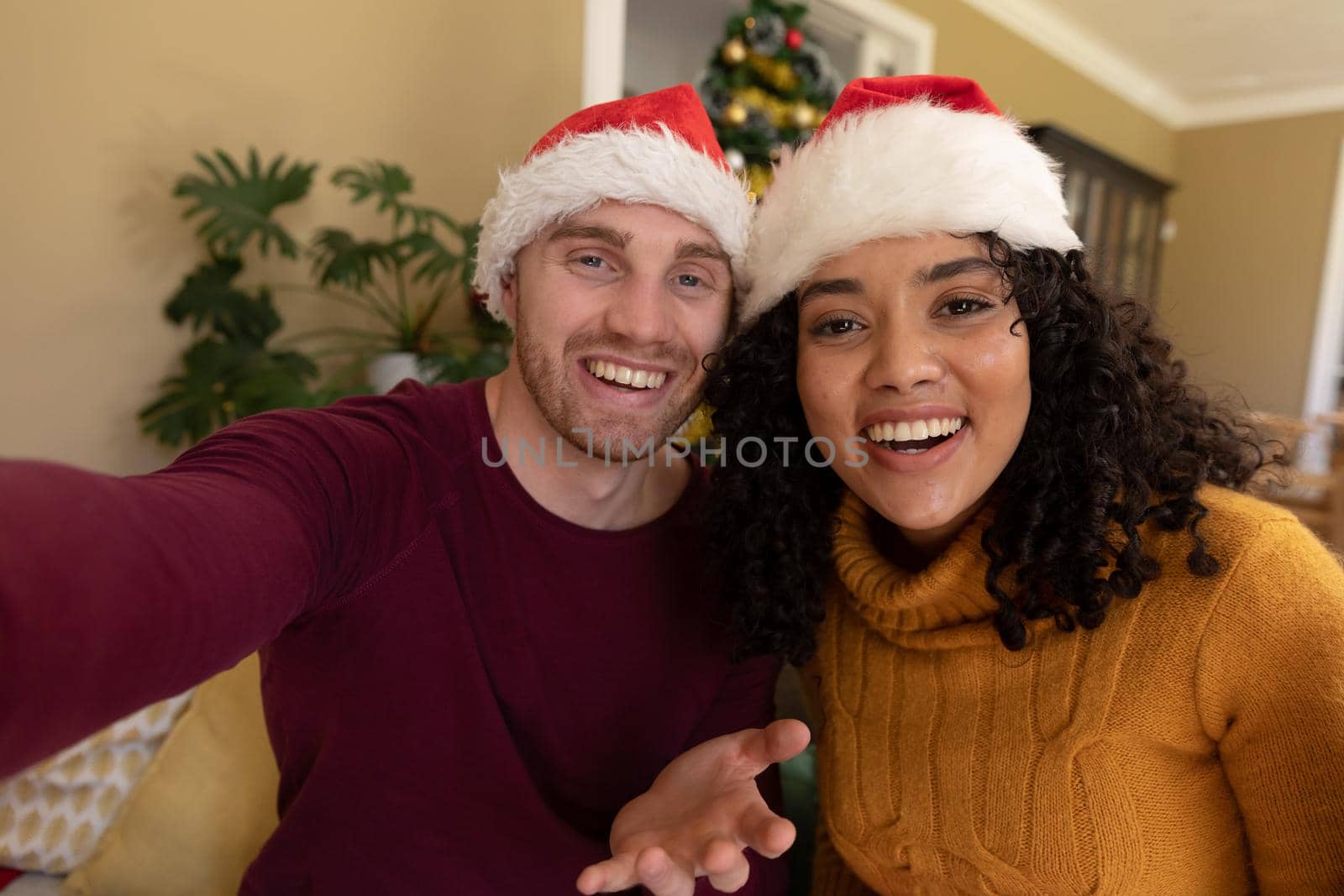 Two happy diverse female and male friends in santa hats having video call at christmas time by Wavebreakmedia