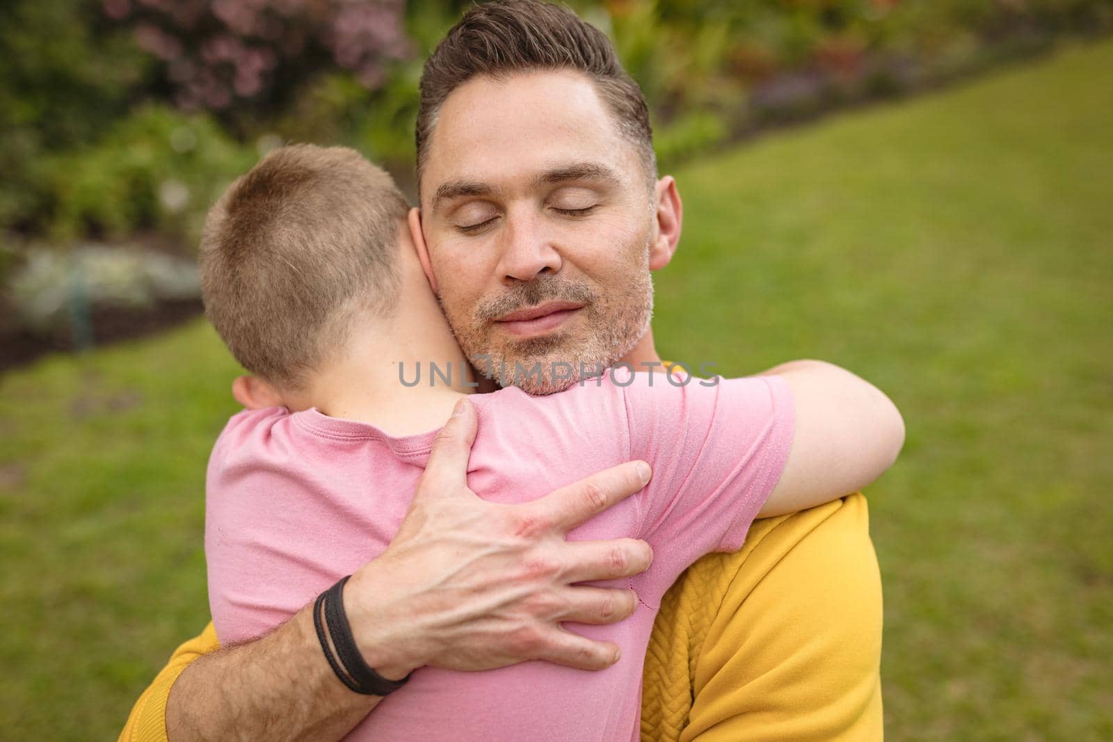 Close up view of caucasian father and son hugging each other in the garden. fatherhood and love concept