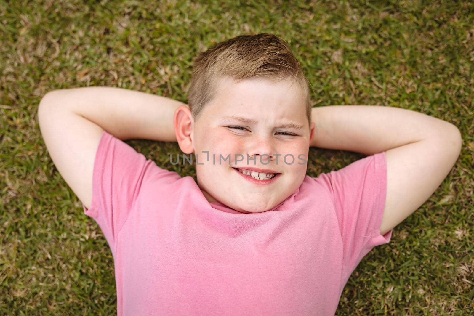 Portrait of caucasian boy smiling while laying on the grass in the garden by Wavebreakmedia