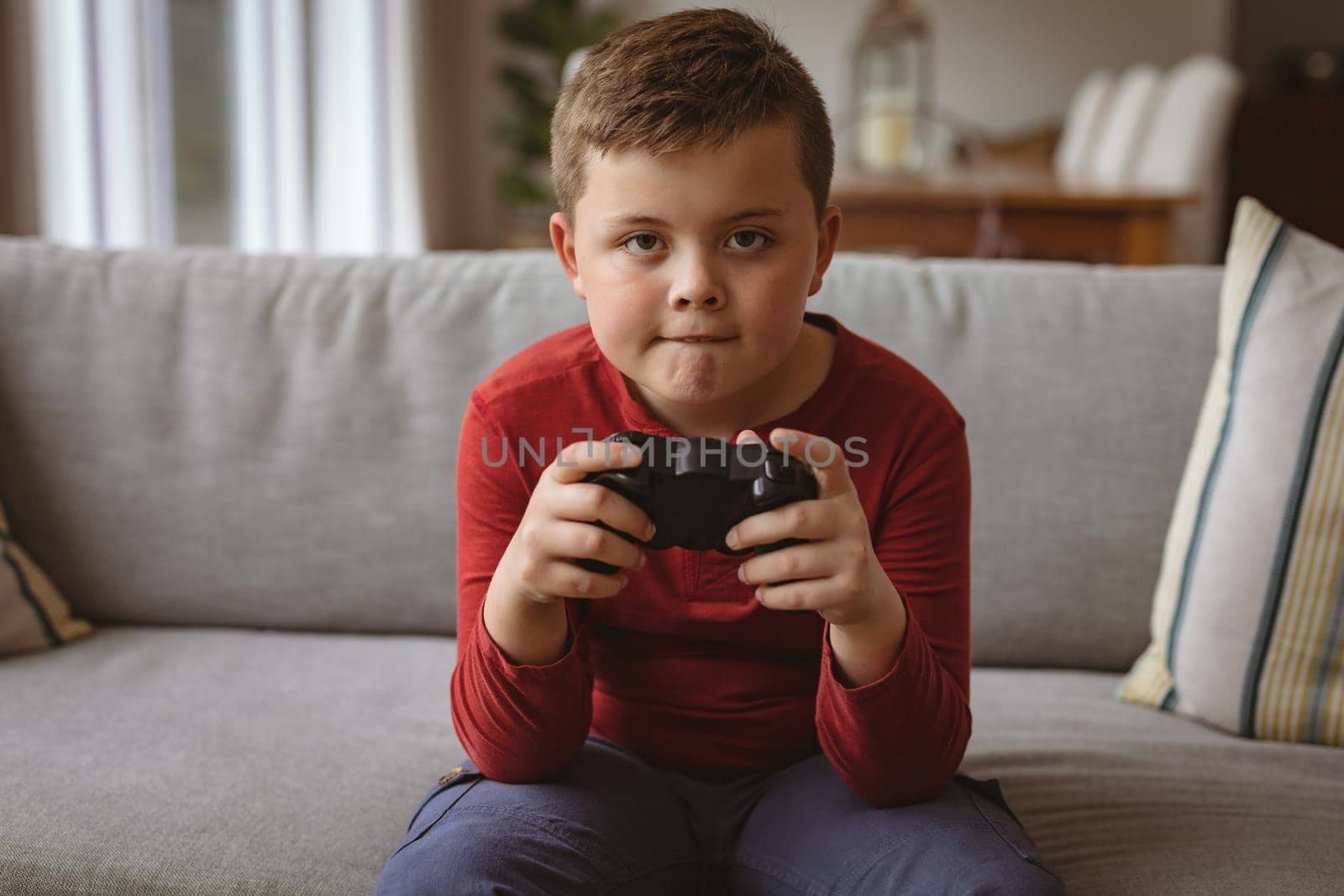 Caucasian boy playing video games sitting on the couch at home by Wavebreakmedia