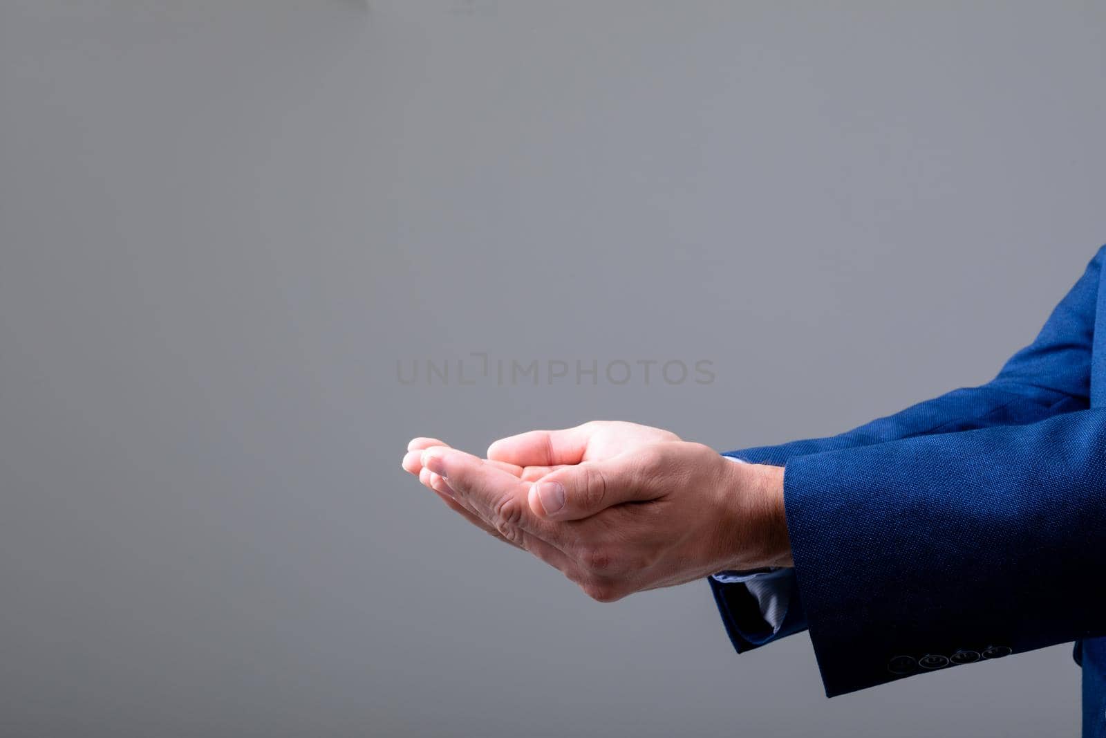 Midsection of caucasian businessman showing his hands, isolated on grey background by Wavebreakmedia