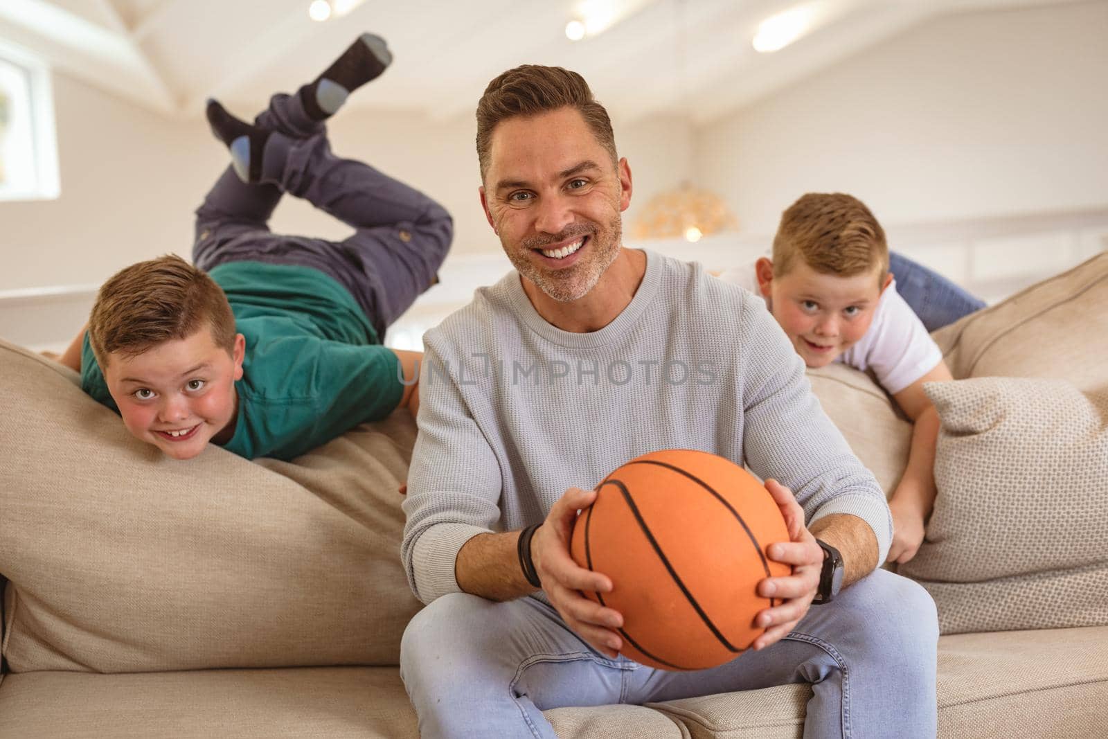 Portrait of caucasian father and two sons with basketball smiling at home by Wavebreakmedia