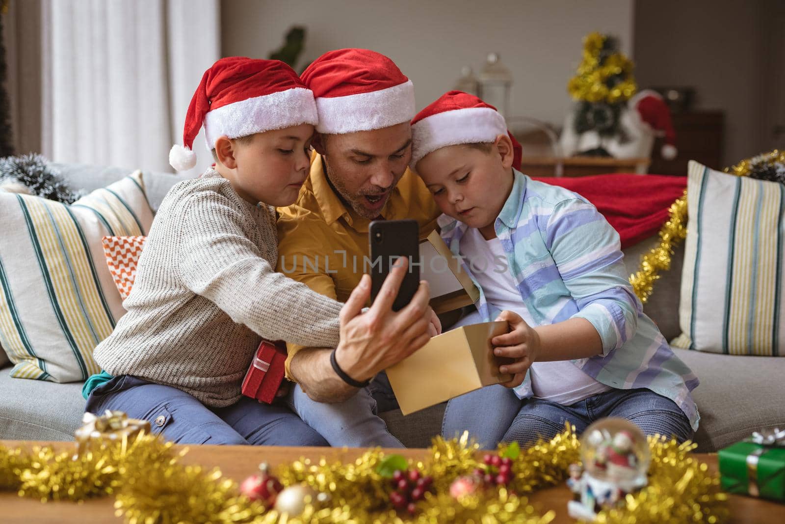 Caucasian father and two sons opening gift box during video call on smartphone during christmas by Wavebreakmedia