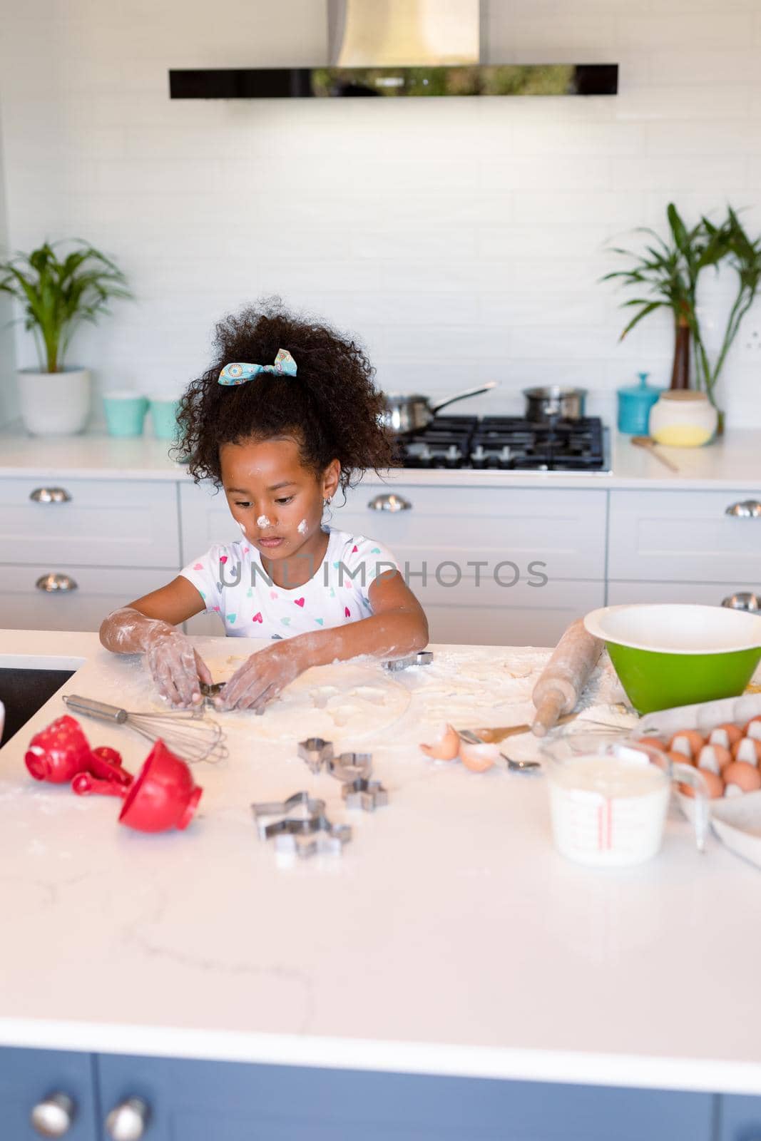 Focused african american messy girl baking in kitchen. baking and cooking, childhood and leisure time at home.
