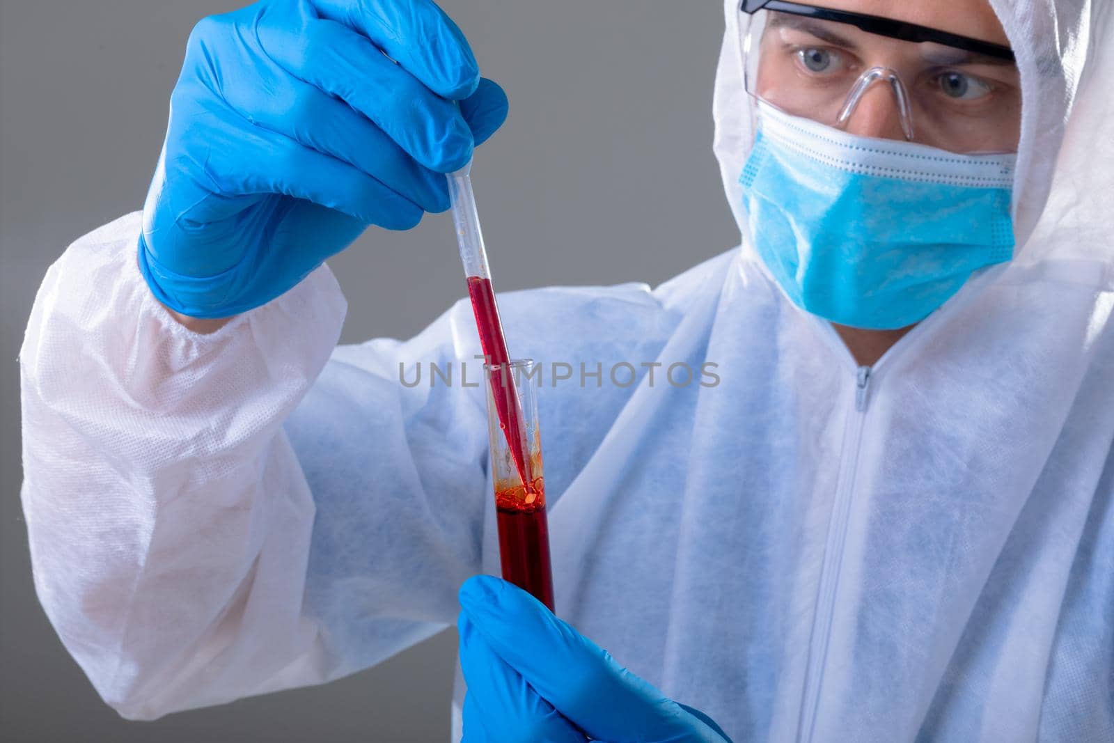 Caucasian male doctor wearing ppe suit holding test-tube. medical and healthcare technology concept during covid 19 coronavirus pandemic concept digitally generated composite image.