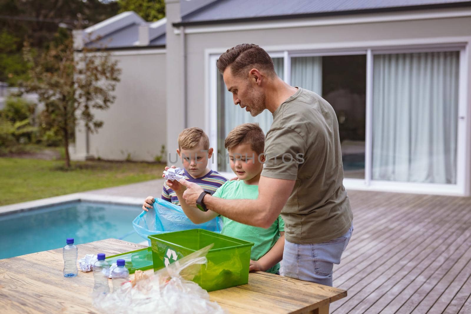 Caucasian father and two sons collecting plastic materials in a bag outdoors. plastic recycling and pollution control concept