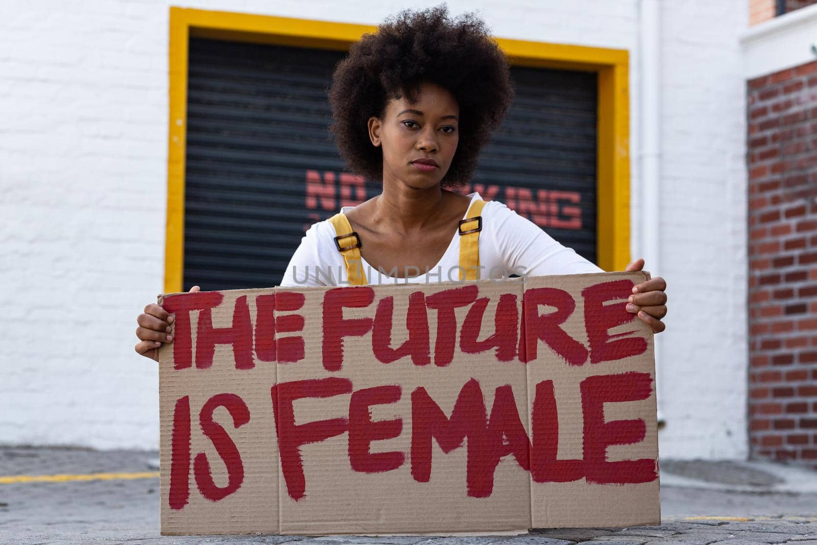 Portrait of mixed race woman holding placard. equal rights and justice protestors on demonstration march.