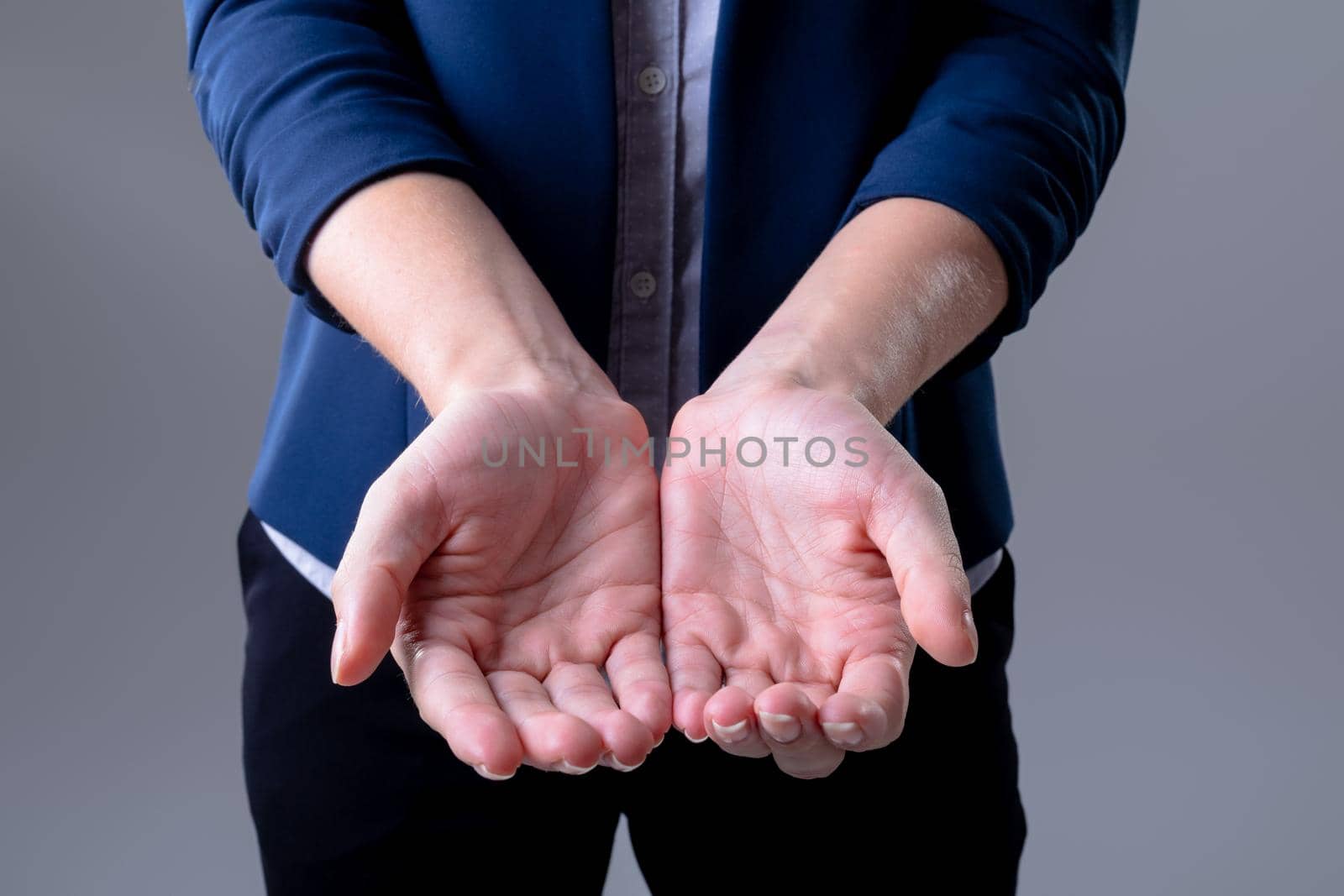 Midsection of caucasian businesswoman showing her hands, isolated on grey background by Wavebreakmedia