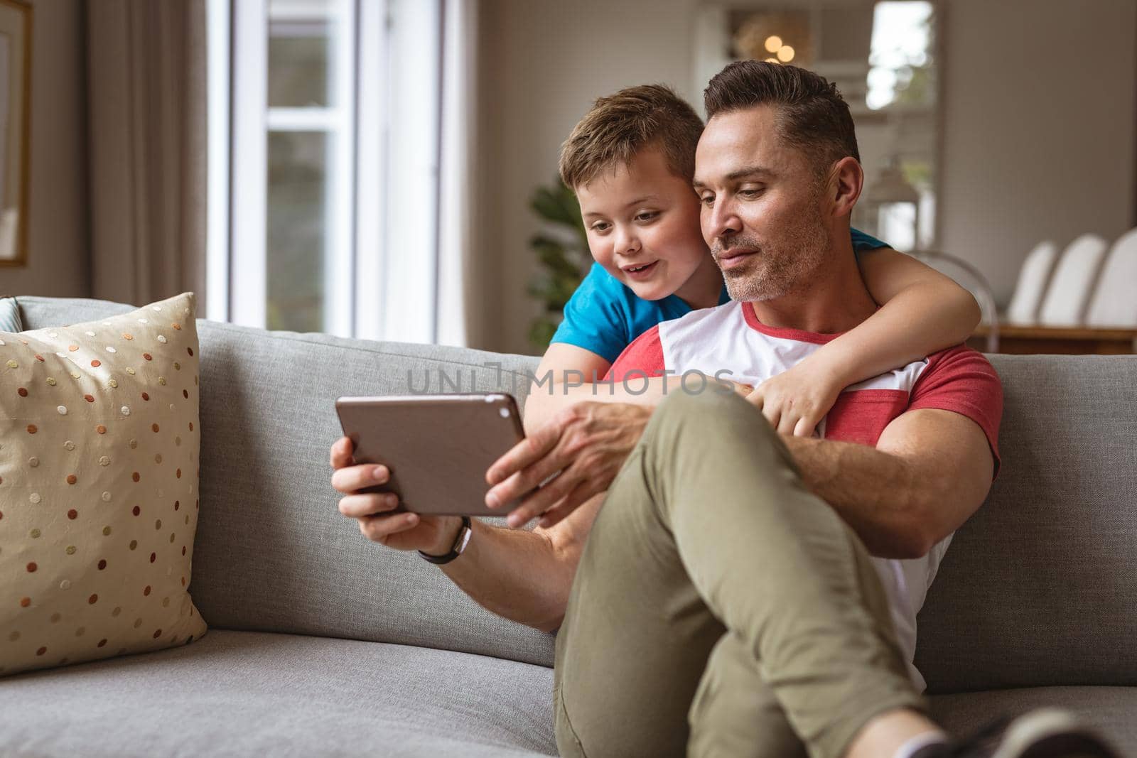 Caucasian father and son using digital tablet on the couch at home by Wavebreakmedia