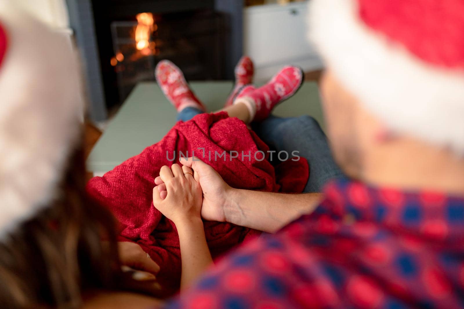 Back view of caucasian couple wearing santa hats and christmas socks at christmas time. family christmas time and festivity together at home.