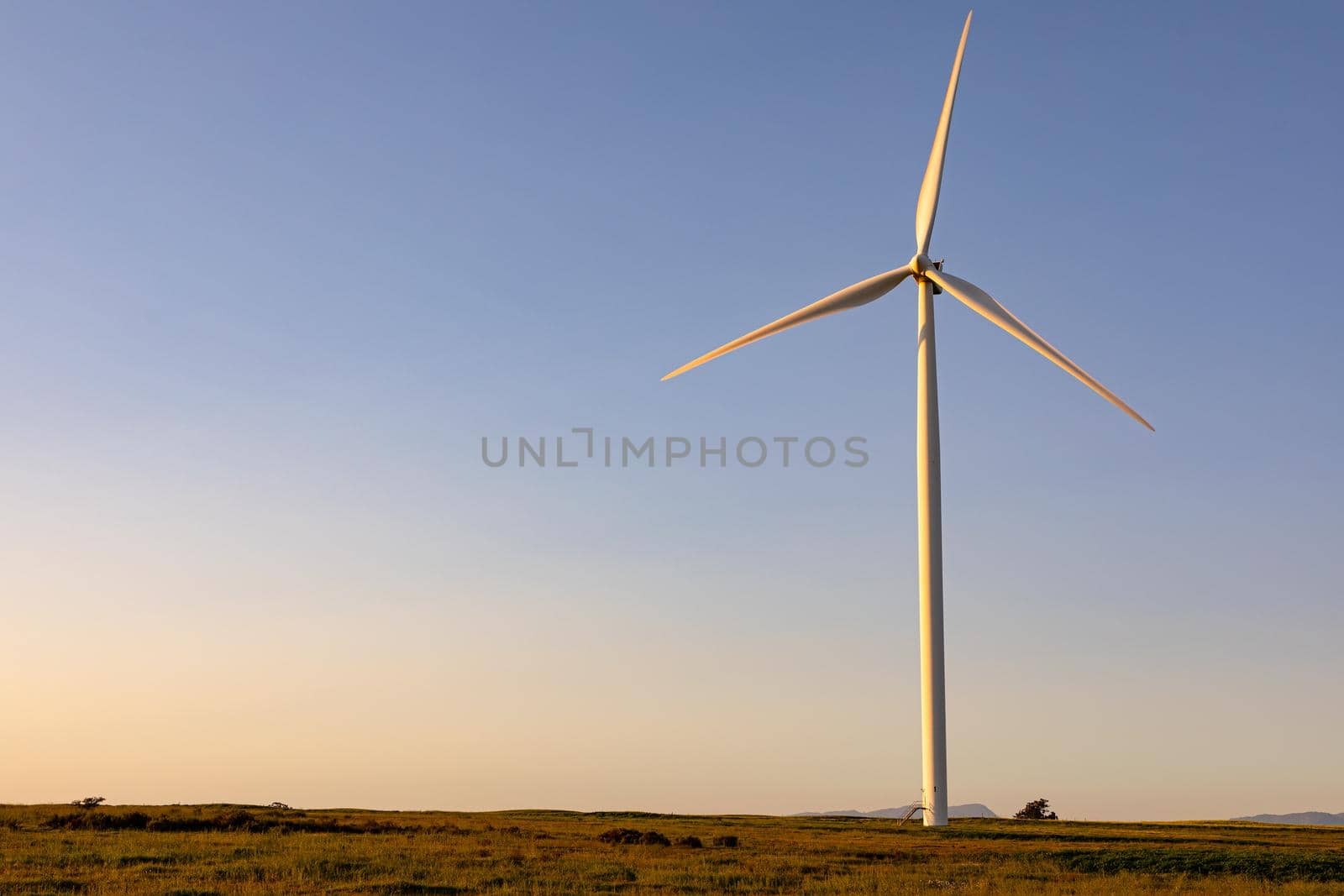 General view of wind turbine in countryside landscape with cloudless sky. environment, sustainability, ecology, renewable energy, global warming and climate change awareness.
