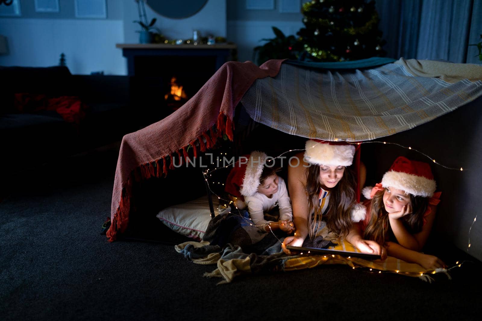 Happy caucasian mother, daughter and son wearing santa hats using tablet at christmas time by Wavebreakmedia