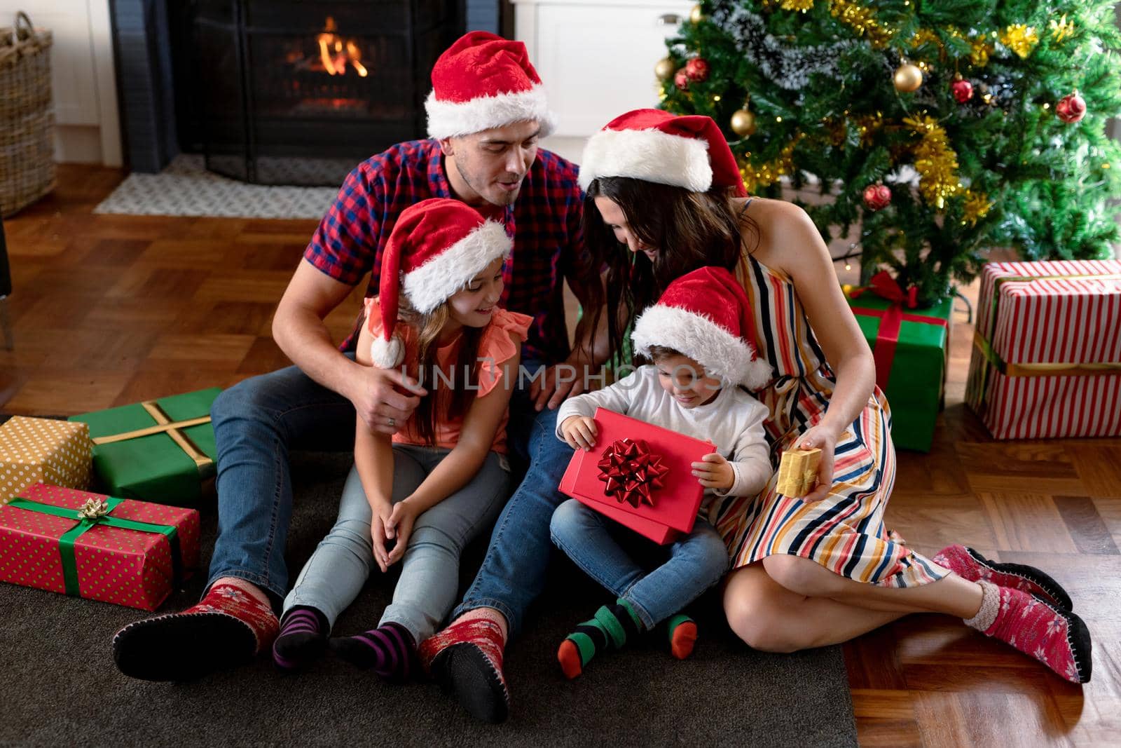 Happy caucasian family wearing santa hat, holding presents at christmas time by Wavebreakmedia