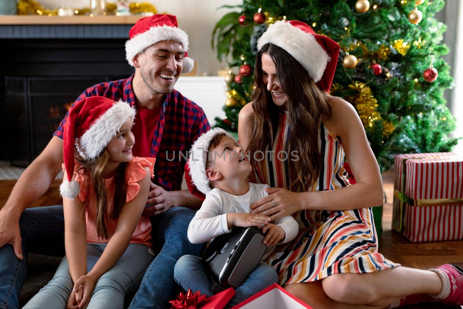 Happy caucasian family wearing santa hat, unpacking presents at christmas time by Wavebreakmedia