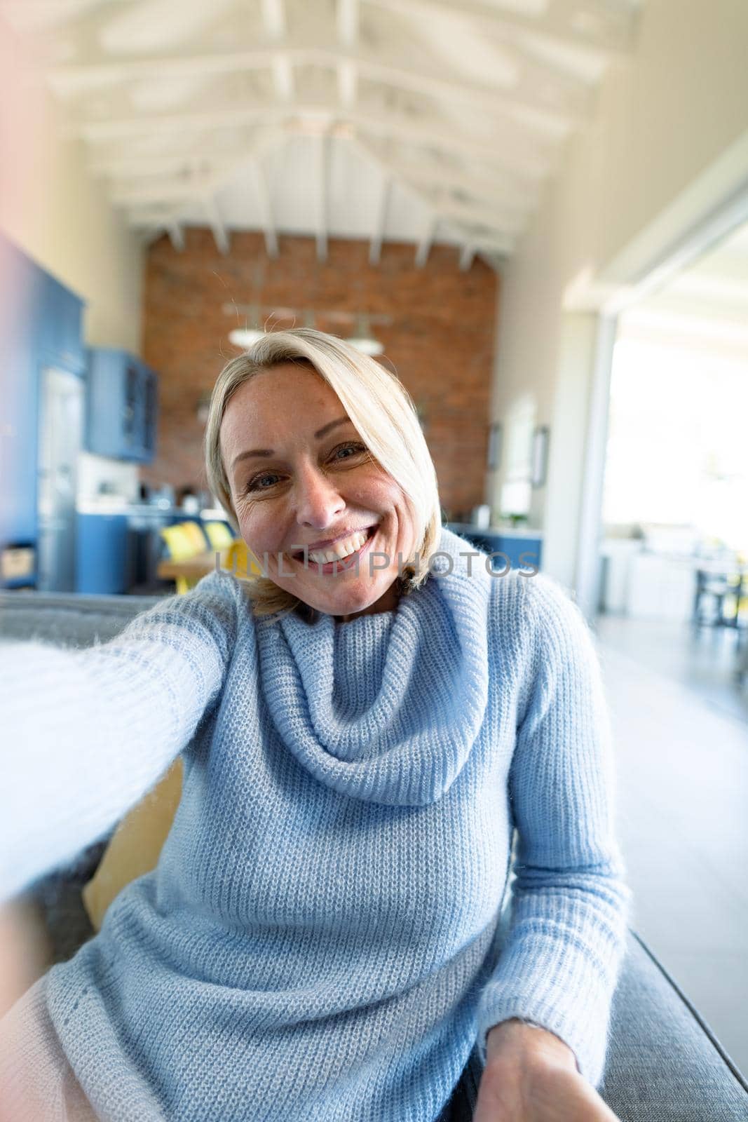 Happy senior caucasian woman in living room sitting on sofa, making video call. retirement lifestyle, at home with technology.