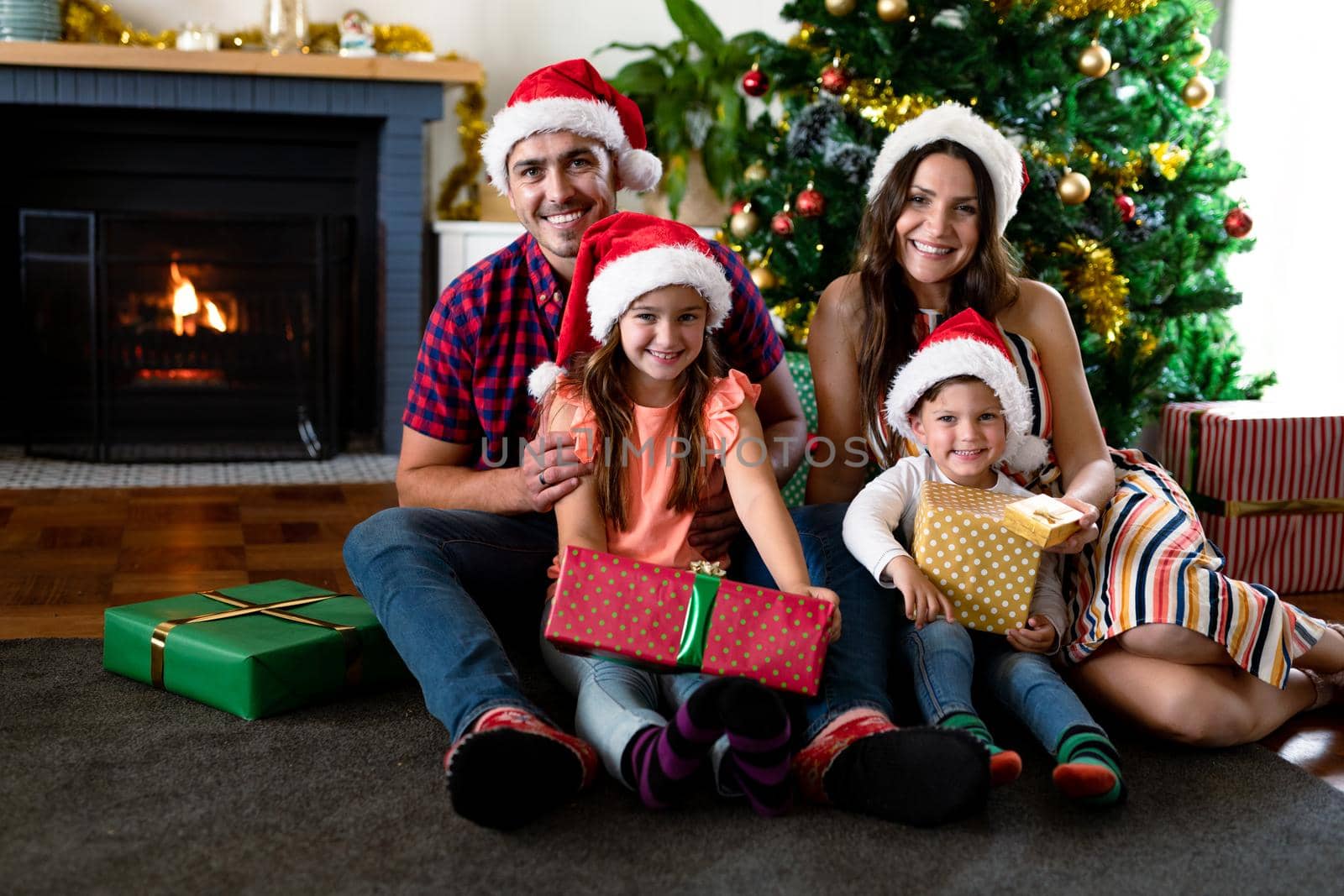 Happy caucasian family wearing santa hat, holding presents, looking at camera at christmas time by Wavebreakmedia