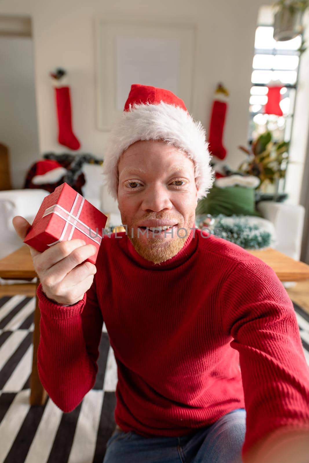 Albino african american man wearing santa hat making video call with christmas decorations by Wavebreakmedia