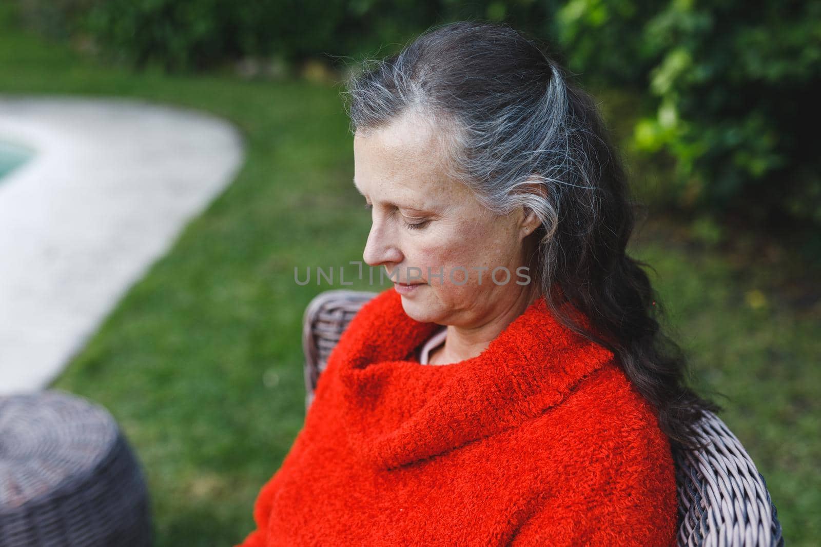 Happy senior caucasian woman sitting on chair in garden. retirement lifestyle, spending time alone at home.