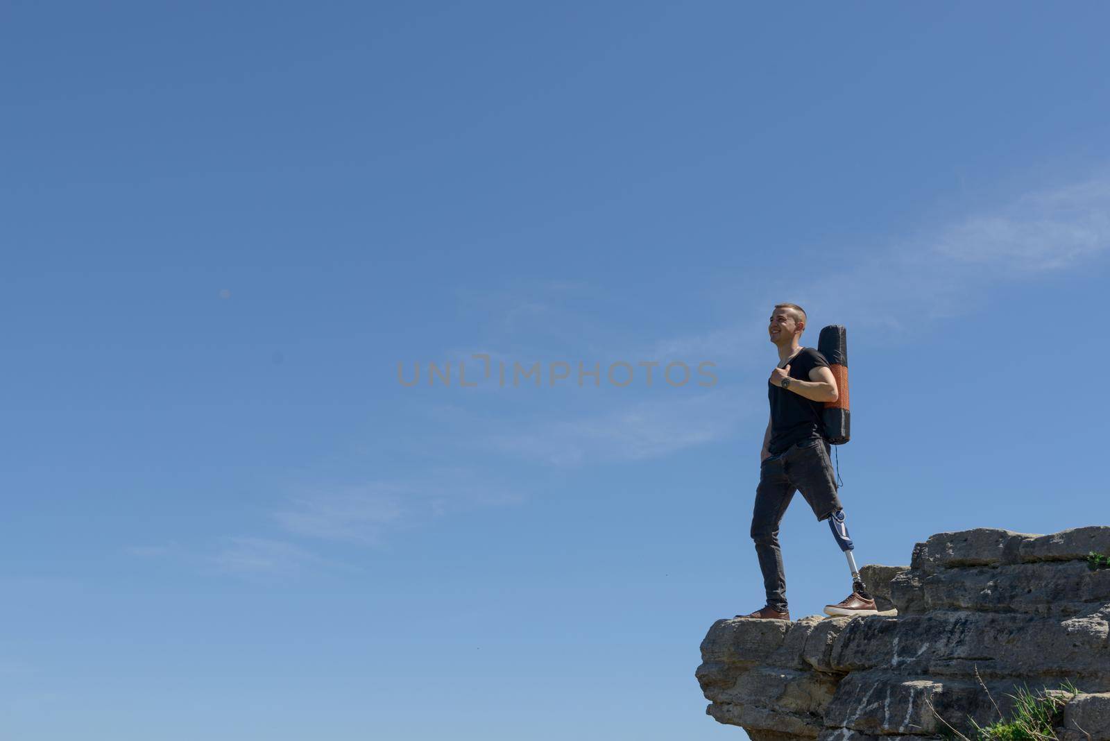 a man on a prosthetic leg travels the mountains. Dressed in black jeans and a T-shirt, he carrying mat by Ashtray25