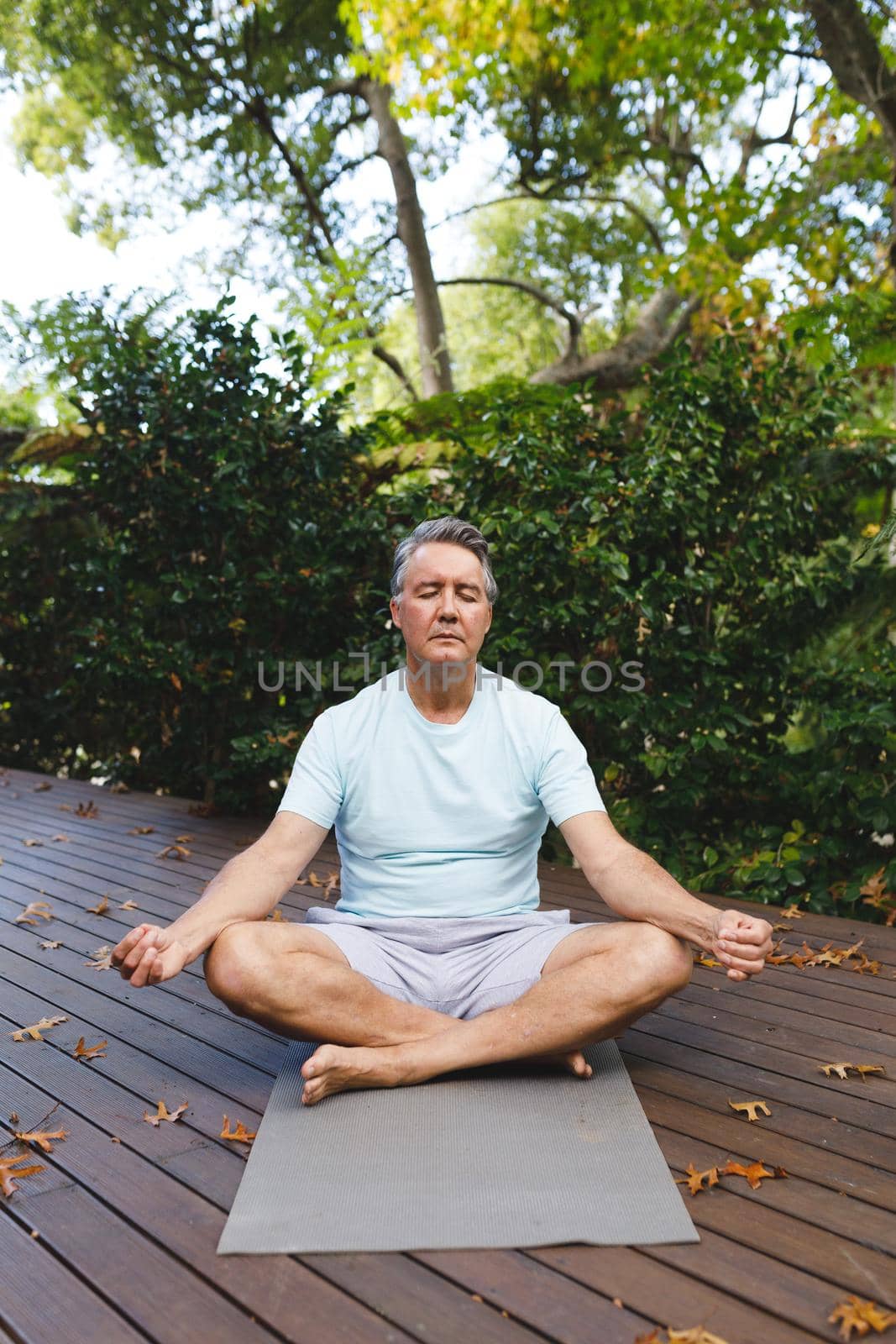 Relaxed senior caucasian man practicing yoga, meditating in garden. healthy retirement lifestyle, spending time self caring at home.