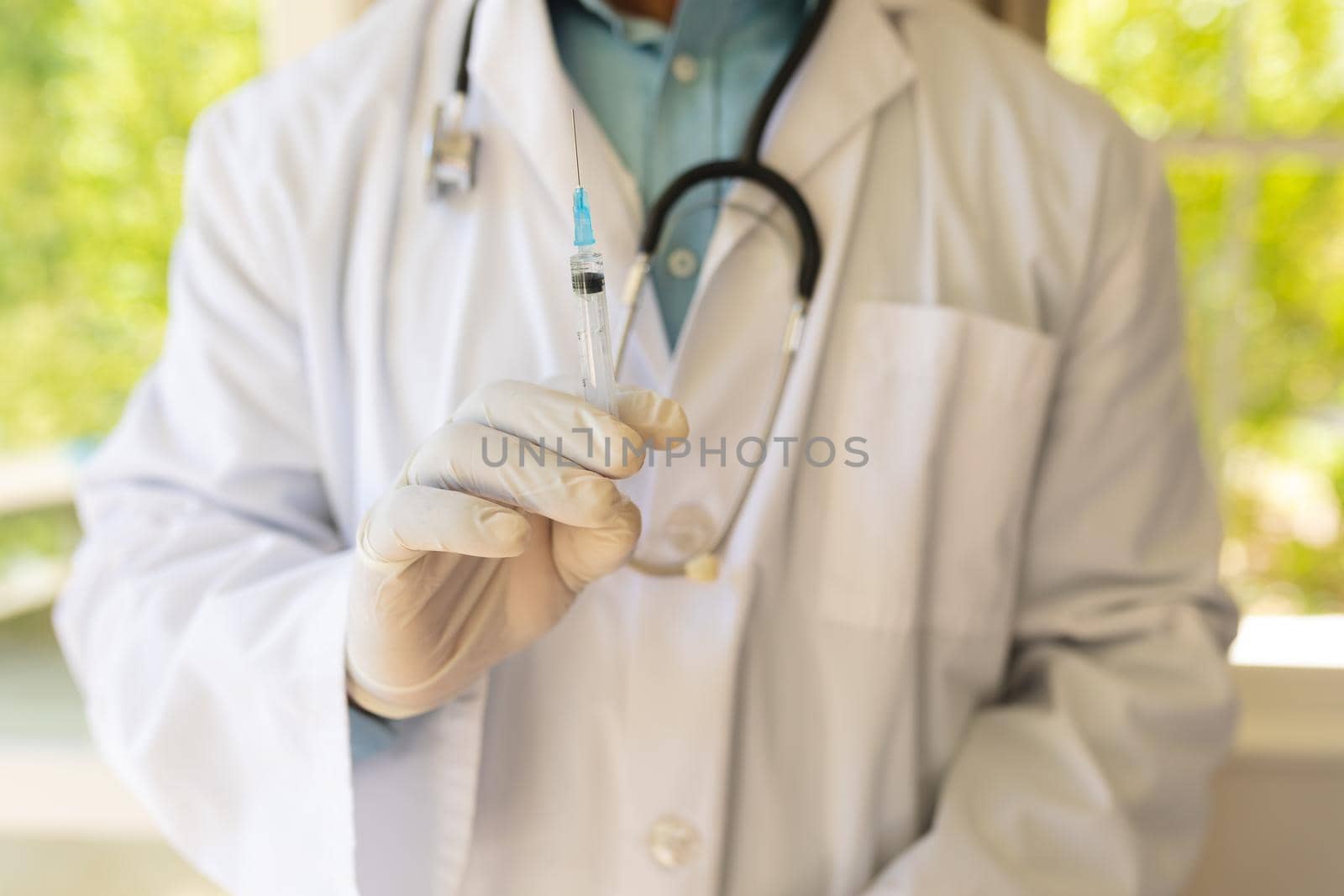 Midsection of senior african american male doctor in gloves preparing vaccination by Wavebreakmedia