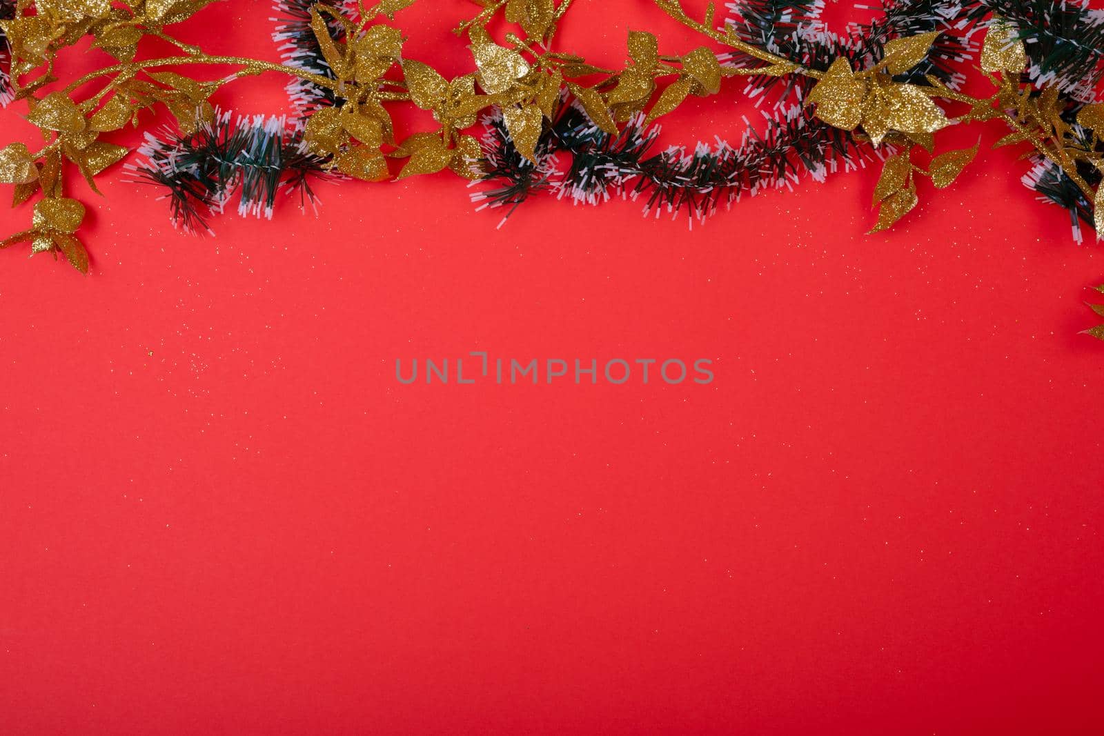 Composition of christmas decorations with garland and copy space on red background. christmas, tradition and celebration concept.