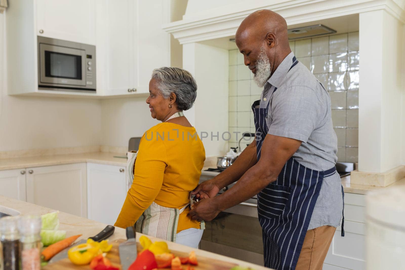 Senior african american couple cooking together in kitchen smiling. retreat, retirement and happy senior lifestyle concept.