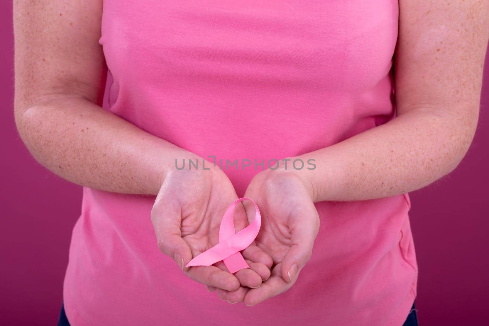 Hands of caucasian woman in pink tshirt holding pink ribbon by Wavebreakmedia