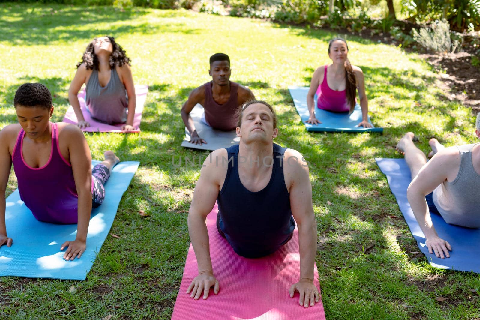 Group of diverse female and male people practicing yoga outdoors. fitness and healthy, active lifestyle.