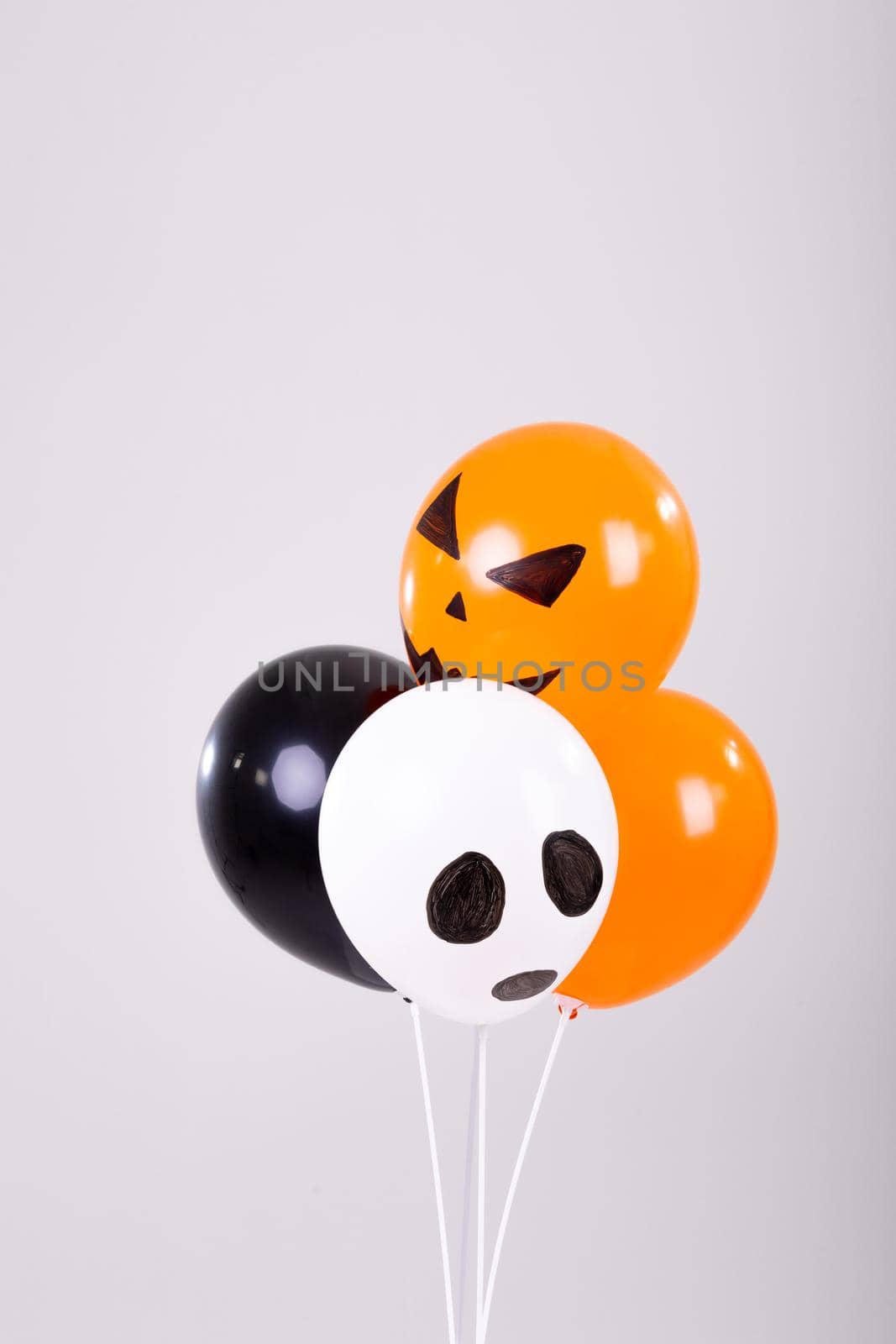 Orange, black and white halloween balloons over white background. halloween tradition and celebration concept digitally generated image.