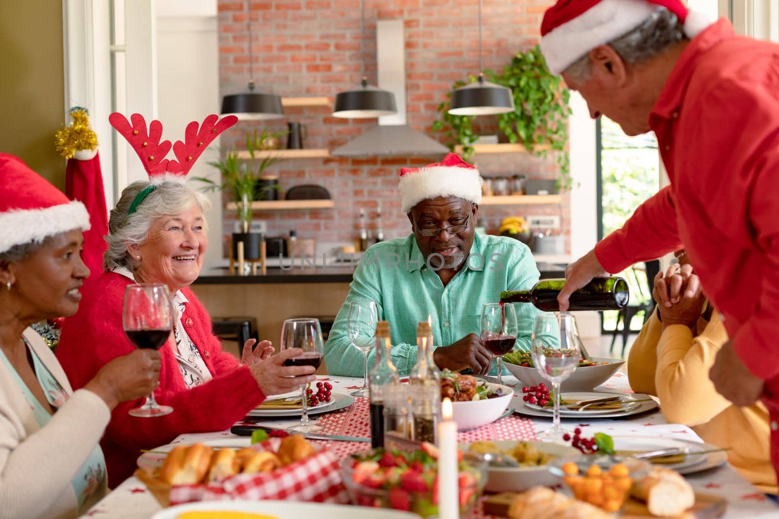Diverse group of happy senior friends celebrating christmas with vine together at home by Wavebreakmedia