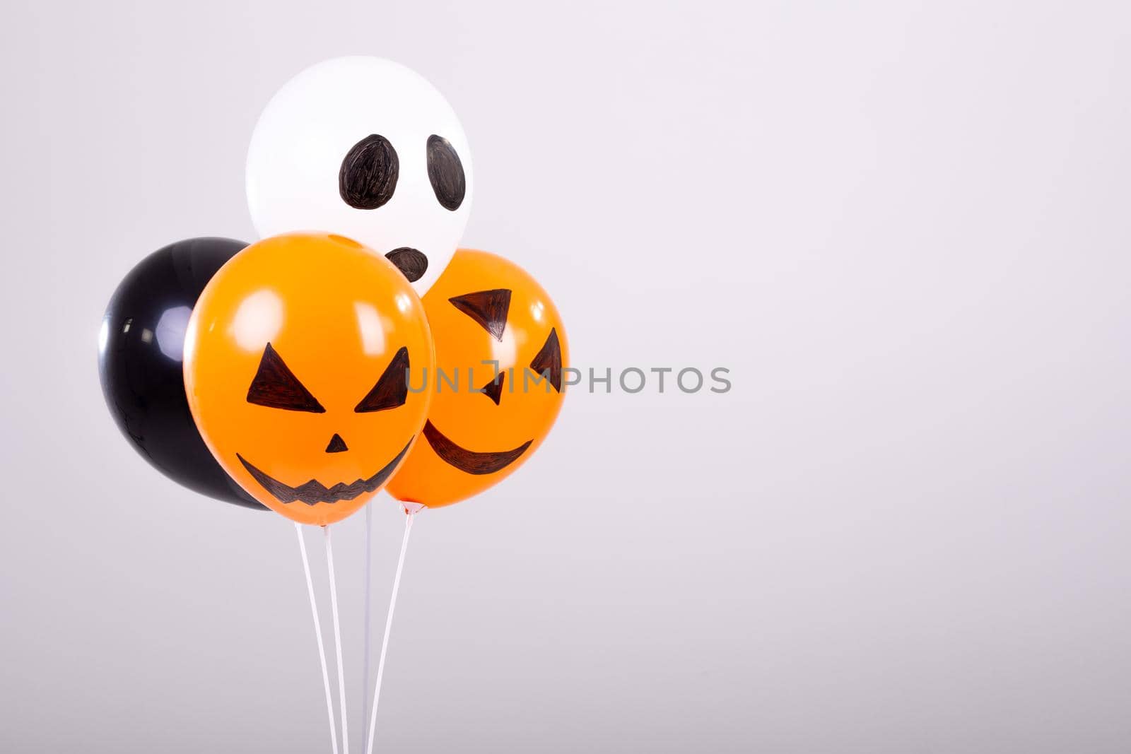 Orange, black and white halloween balloons over white background. halloween tradition and celebration concept digitally generated image.
