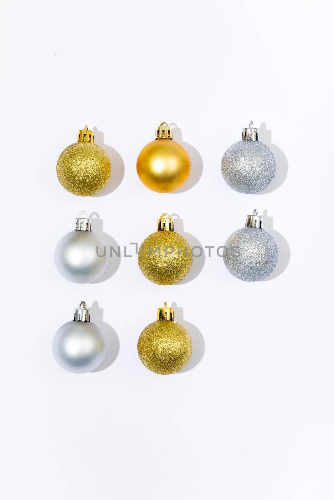 Composition of three gold and silver baubles on white background. christmas, tradition and celebration concept.