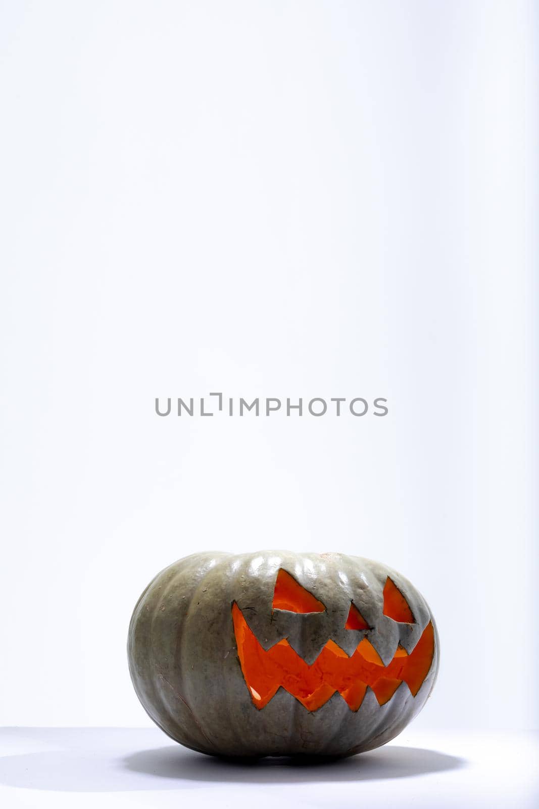 Composition of lit scary halloween carved green pumpkin with copy space on white background by Wavebreakmedia